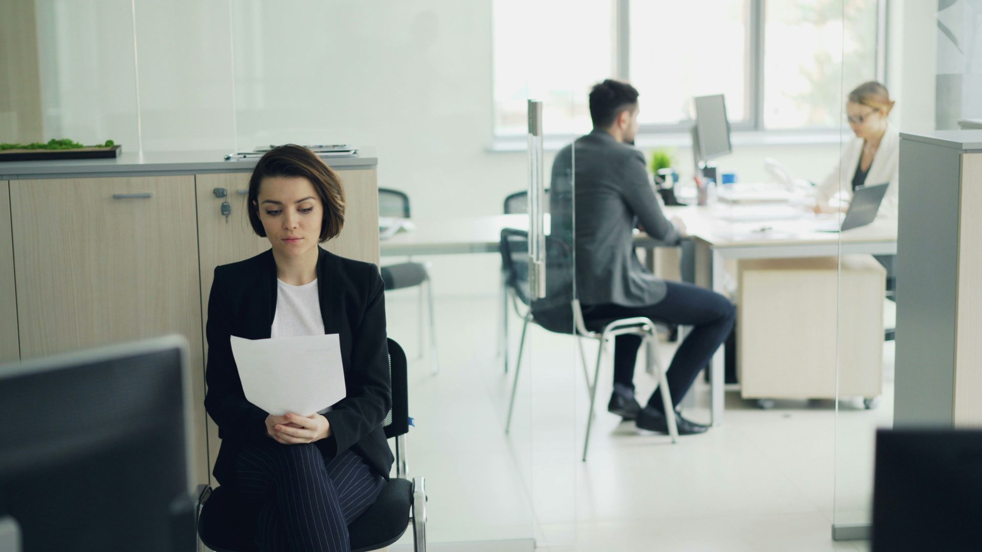 Frau sitzt im Büro und hält Papiere in der Hand